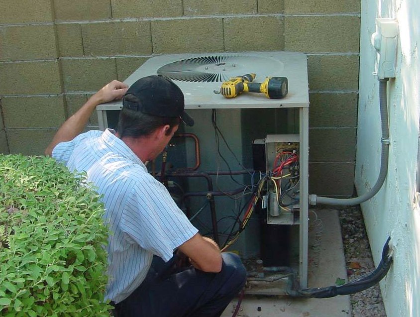 Technician performing AC replacements in Atlanta GA on outdoor HVAC condenser unit.